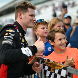 Josef Newgarden poses with a fan on pit road at Indianapolis Motor Speedway