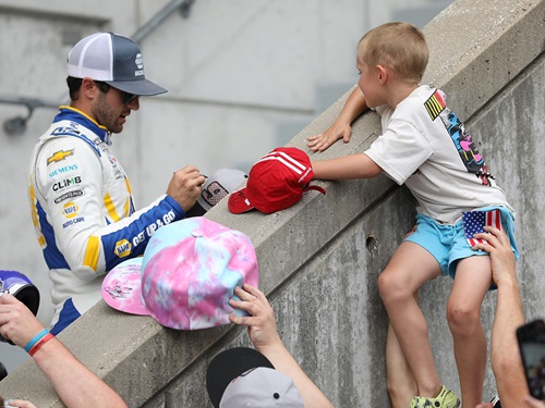 A child gets an autograph from a NASCAR Driver