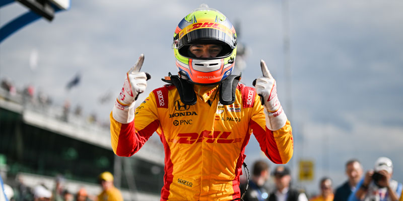 Alex Palou celebrates winning pole position in firesuit and helmet